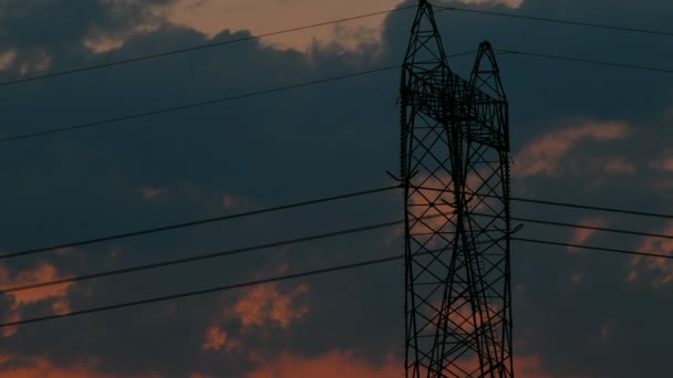 Silhuetten av högspänning elektriska pylon, tower i solnedgång, tidsinställd av moln som rör sig bakom pylon, 4k Uhd — Stockvideo