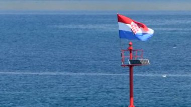 Deniz feneri ve gün ışığında bayrak uçan taş iskele, sabit