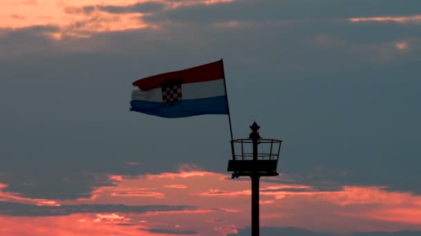 Muelle de piedra con faro y bandera al atardecer, zoom — Vídeos de Stock