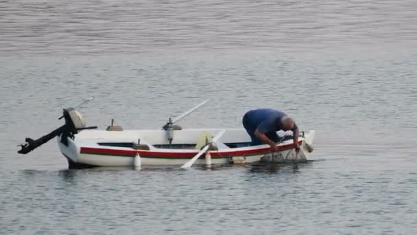 Vieux pêcheur traditionnel en Croatie sur un petit bateau en bois attrapant du poisson avec cage de pêche, nacelle — Video