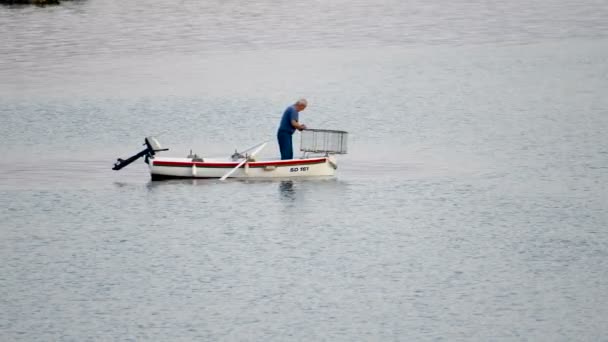 Antiguo pescador tradicional en Croacia en un pequeño barco de madera la captura de peces con jaula de pesca, vaina — Vídeos de Stock