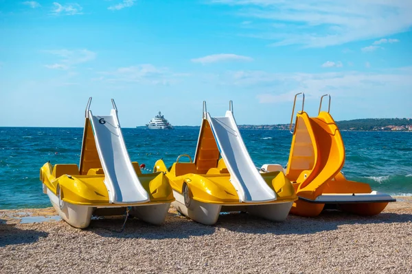 Барвисті педальні човни, жовті педоліно на пляжі — стокове фото