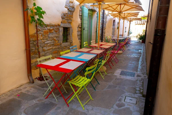 Small caffee, restaurant in narrow street in a medieval town with colorful tables and chairs