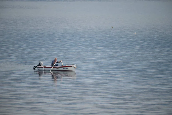 Antiguo pescador tradicional en Croacia en un pequeño barco de madera de nuevo en el puerto temprano en la mañana — Foto de Stock