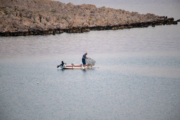 Velho pescador tradicional na Croácia em um pequeno barco de madeira captura de peixe com gaiola de pesca, pod — Fotografia de Stock