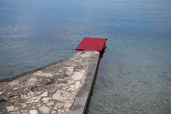 Pier de pedra com tapete vermelho à beira-mar, conceito de praia de luxo — Fotografia de Stock