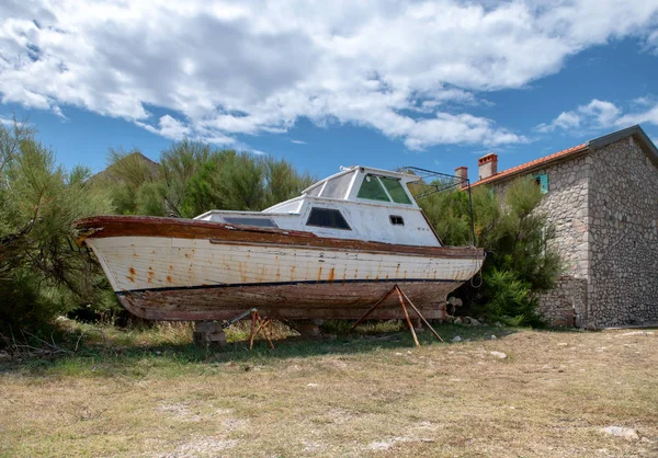 Заброшенная лодка на берегу каменный дом на заднем плане — стоковое фото