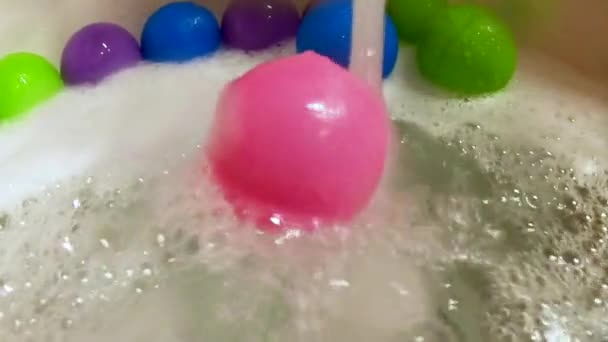 Pink plastic ball rolled by water stream in bath tub, slow motion — Stock Video