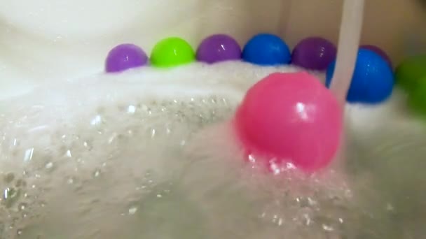 Рожевий пластиковий м'яч, що прокатується водяним потоком у ванній, повільний рух — стокове відео