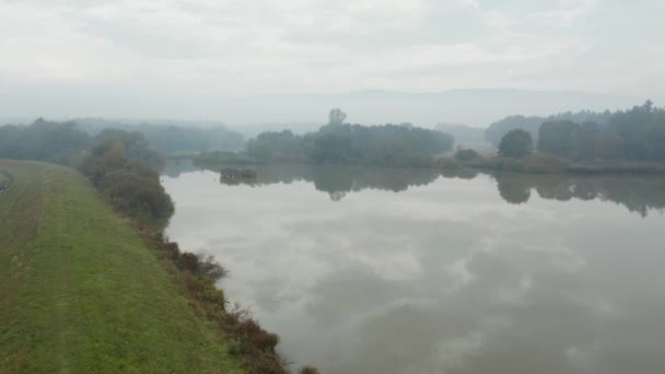 Panning shot di un bellissimo lago riflettente nella campagna slovena in una nebbiosa mattina d'autunno — Video Stock