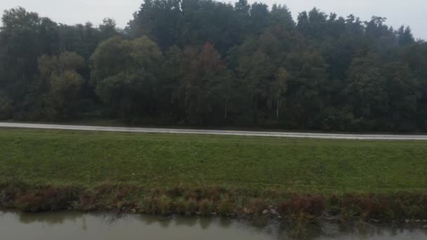 Letecký pohled na prázdnou cestu podél travnatého pahorku nad jezerem s podzimní stromy — Stock video