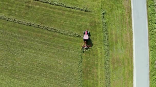 Vista aérea de arriba hacia abajo de un tractor rojo cultivando tierras de cultivo con una cuchilla giratoria en la Eslovenia rural — Vídeo de stock