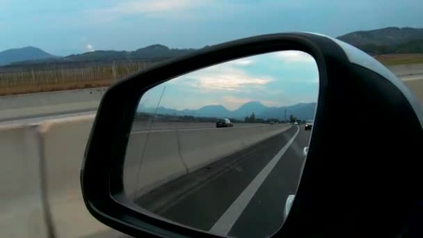 Vista en el espejo trasero del coche en la carretera — Vídeo de stock