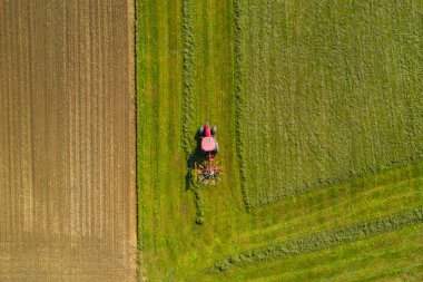 Red tractor windrowing hay, top down aerial view clipart
