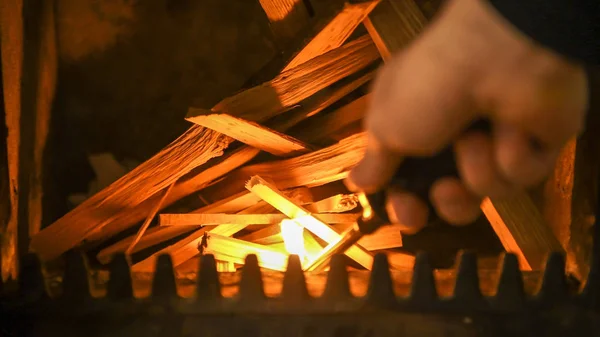 ストーブ、男性の手で薪の山に火をつけるライターの火を開始 — ストック写真