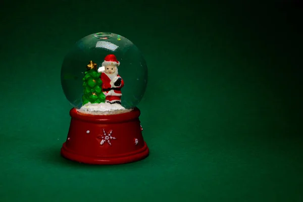 Санта в снежном глобусе изолирован на зеленом — стоковое фото