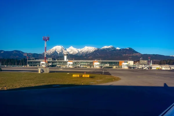 Ljubljana Airport asfalt, terminal ve arka planda dağlar