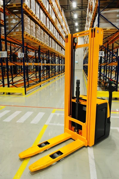 Depoda, endüstriyel depolama raf arka planda sarı forklift