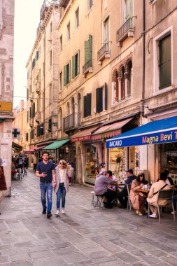 Eski, tarihi binalar, mağazalar ve kafelerile Venedik sokaklarında dolaşan turistler