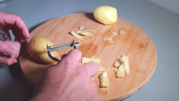 Händerna på far och dotter håller skalaren och peeling potatis — Stockvideo