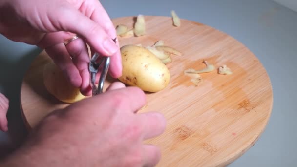 Händerna på far och dotter håller skalaren och peeling potatis — Stockvideo