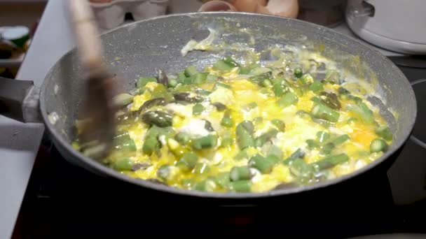 Green asparagus in frying pan with eggs and onions — Stock Video