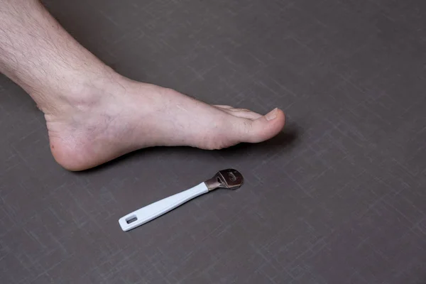 Man removing corn, callus from his feet using a razor file, masculine skin care, skin disease, fungal infection, skin treatment