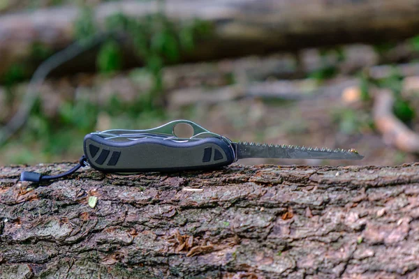 多工具户外设备，瑞士士兵刀与延长锯片在树干在森林 — 图库照片
