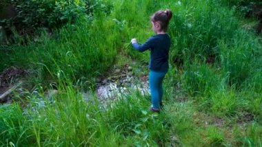 Doğada bir bıçakla oynayan küçük kız, ormanda küçük bir dere içine çim kesme, oudoor hayatta kalma bıçağı, bir çocuk tarafından kullanılan araç