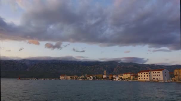 Día a noche lapso de tiempo de la pequeña ciudad costera y puerto, montañas y nubes ondulantes en el fondo — Vídeos de Stock