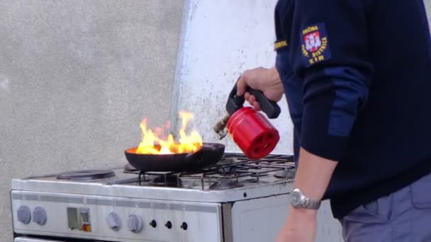 Пожарный зажигает жир в кастрюле на плите — стоковое видео