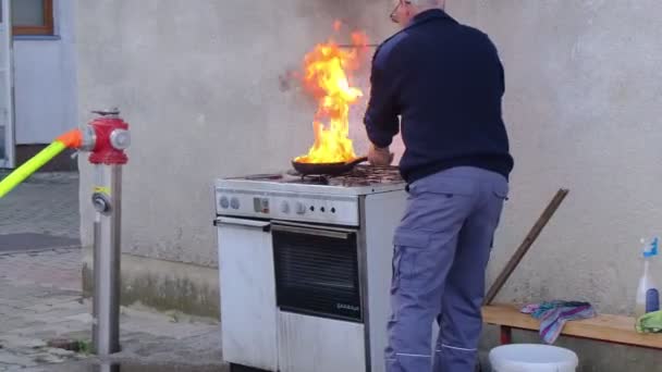 Láng a konyhában, hpt kövér serpenyő a tűz, tűzoltó oltja a tüzet egy fedél — Stock videók