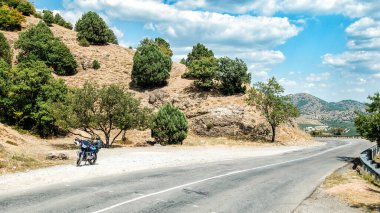 Motosiklet dağ yolunda park edilmiş.