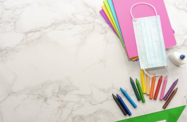 Coronavirus 'tan sonra okula dön. Defterler, koruyucu maskeler, kalemler, mermer zemin üzerindeki hesap makinesi.