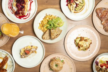 Pankek, yumurta ve kruvasan gibi çeşitli branç tabakları ile dolu ahşap masa.