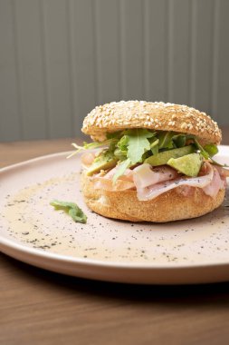 Simitli sandviç, taze prosciutto, kremalı avokado ve susamlı çörek üzerinde canlı roka.
