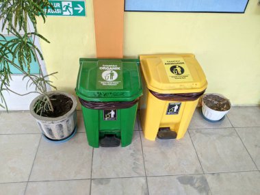 İçeriye yan yana konan organik ve inorganik atık için yeşil ve sarı çöp bidonları atık ayrımcılığını ve çevresel temizliği destekliyor..