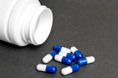 kapsüller (haplar) mavi bir sırt üzerinde beyaz bir şişe den döküldü