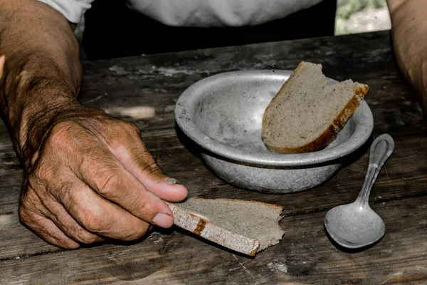 Hands the poor old man\'s, piece of bread and empty bowl on wood