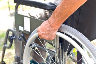 Engelli bir adam tekerlekli sandalyede oturuyor, th ellerini tutar