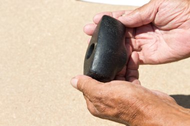 Yaşlı bir adamın elinde tuttuğu eski bir taş çekiç. Arkeoloji