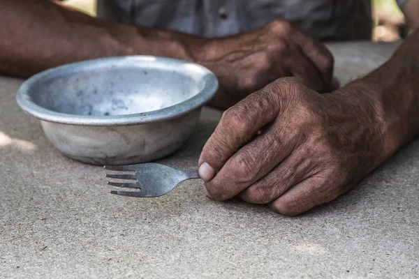 Hungry. Poor old man's hands an empty bowl. Selective focus. Pov — Stock Photo, Image