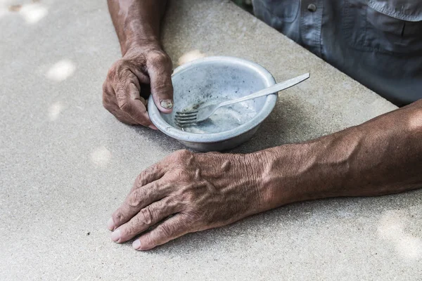 Hungry. Poor old man's hands an empty bowl. Selective focus. Pov — Stock Photo, Image