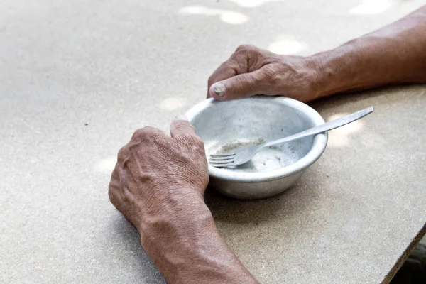 Hungry. Poor old man's hands an empty bowl. Selective focus. Pov — Stock Photo, Image