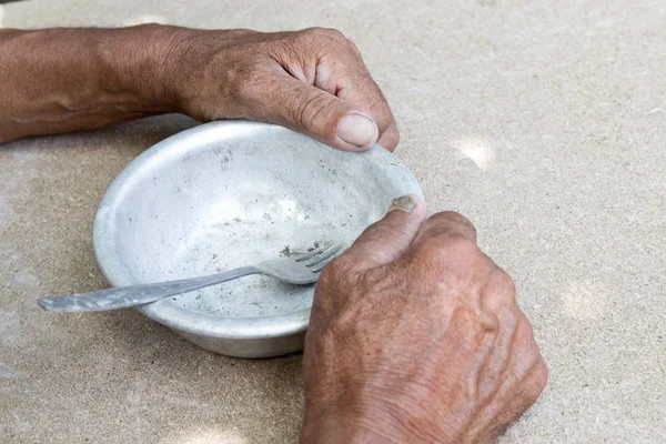 Hungry. Poor old man's hands an empty bowl. Selective focus. Pov — Stock Photo, Image