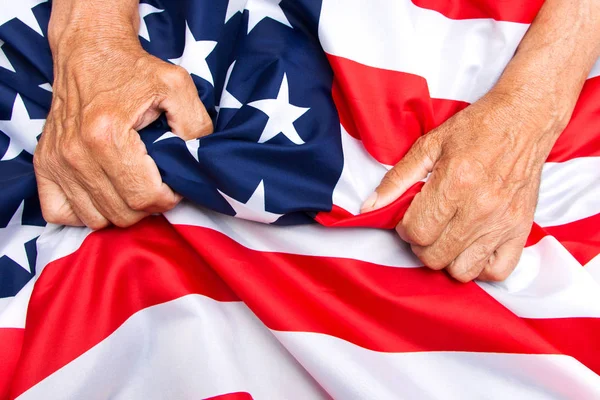 Oudere man handen comprimeert een USA vlag. Stockfoto