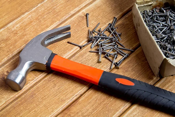 Martillo y clavos esparcidos sobre fondo de madera. Concepto de carpintería — Foto de Stock