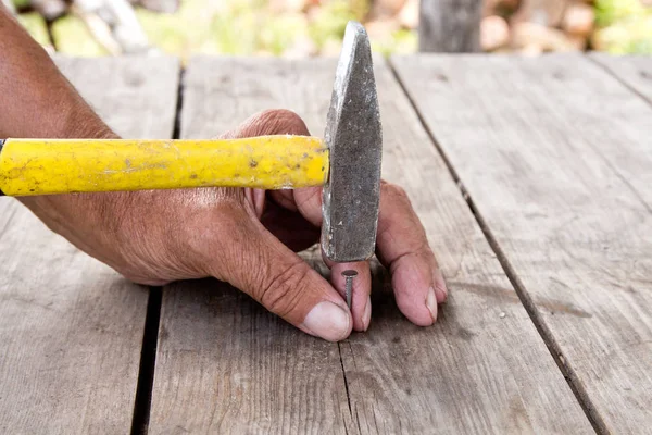 Martillar un clavo con un martillo. Carpintero trabajador mayor — Foto de Stock