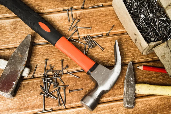 Martillo y clavos esparcidos sobre fondo de madera. Concepto de carpintería — Foto de Stock