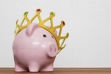 Finansal Galibi veya para tasarruf kavramı, mutlu pembe ahşap masa, en iyi gelecekte yatırım altın bir taç giyen kumbara gülümseyen kralı